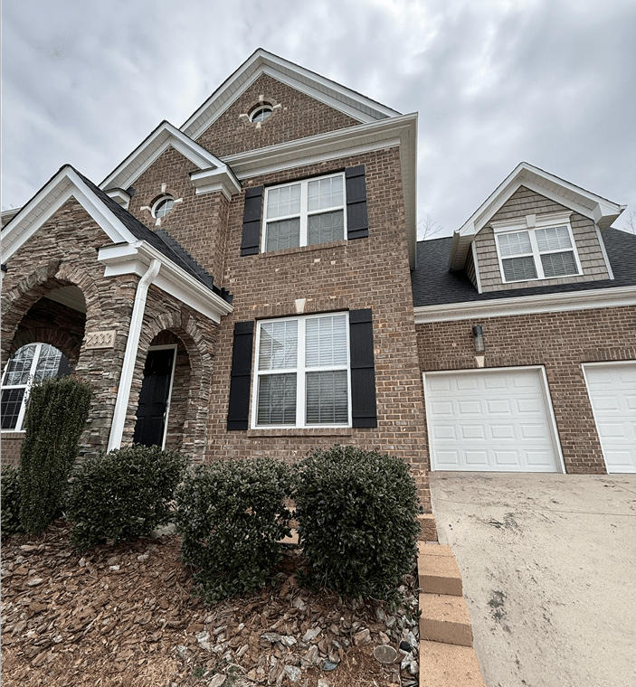 Two-story brick house with garage and shrubs.