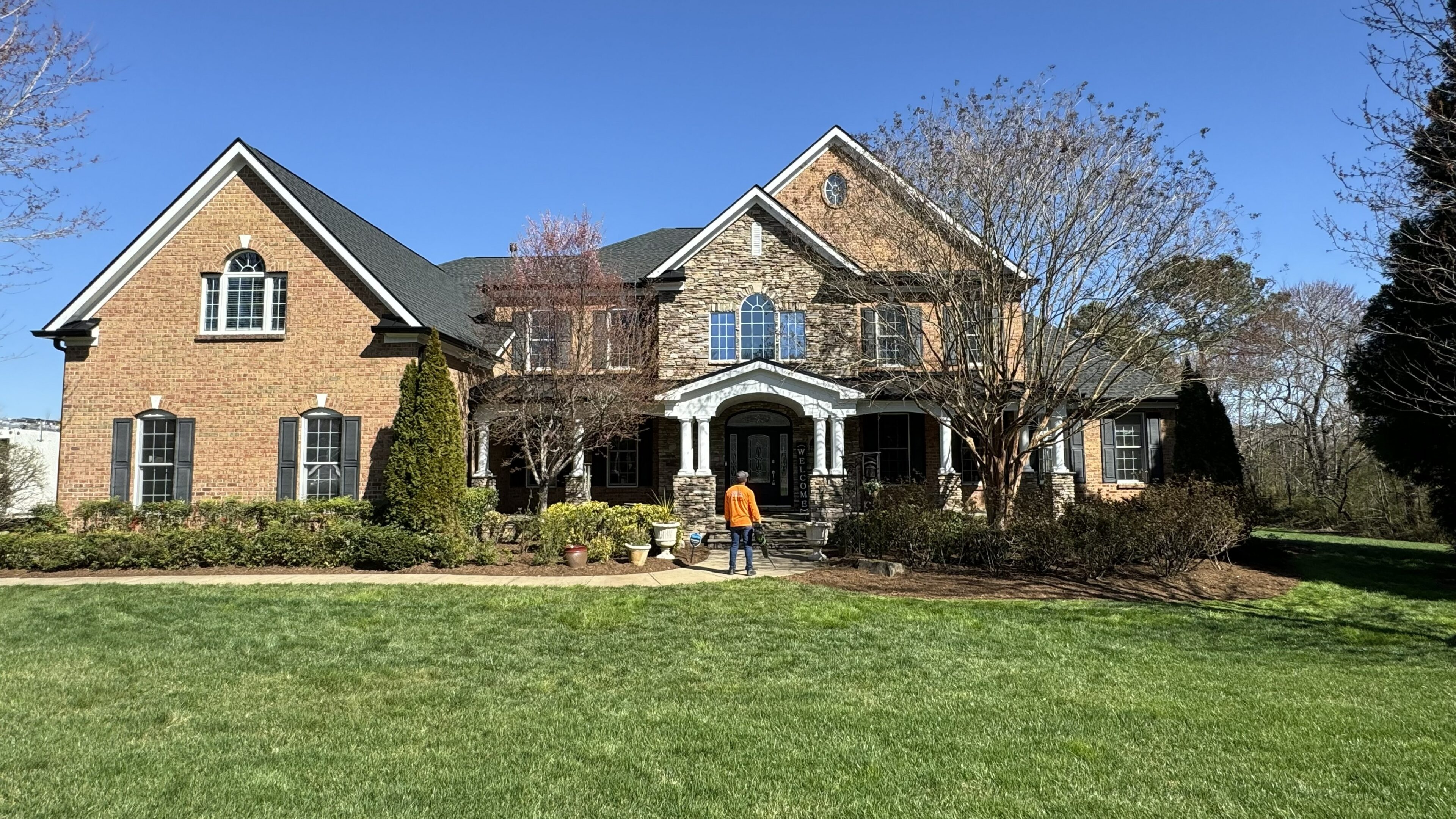 Large brick house with green lawn.