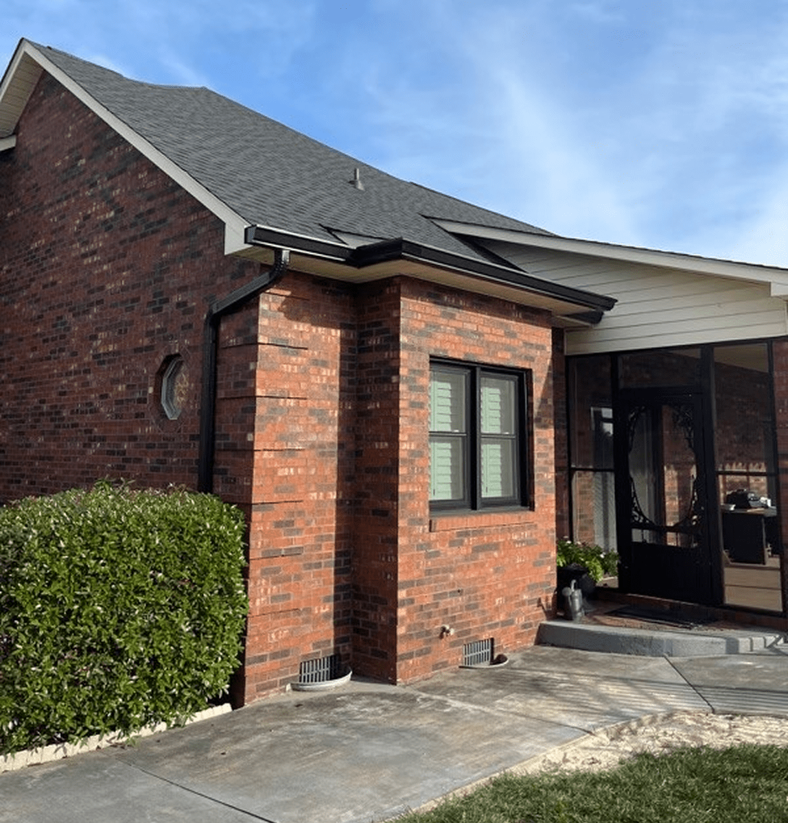 Red brick house with black roof shingles.