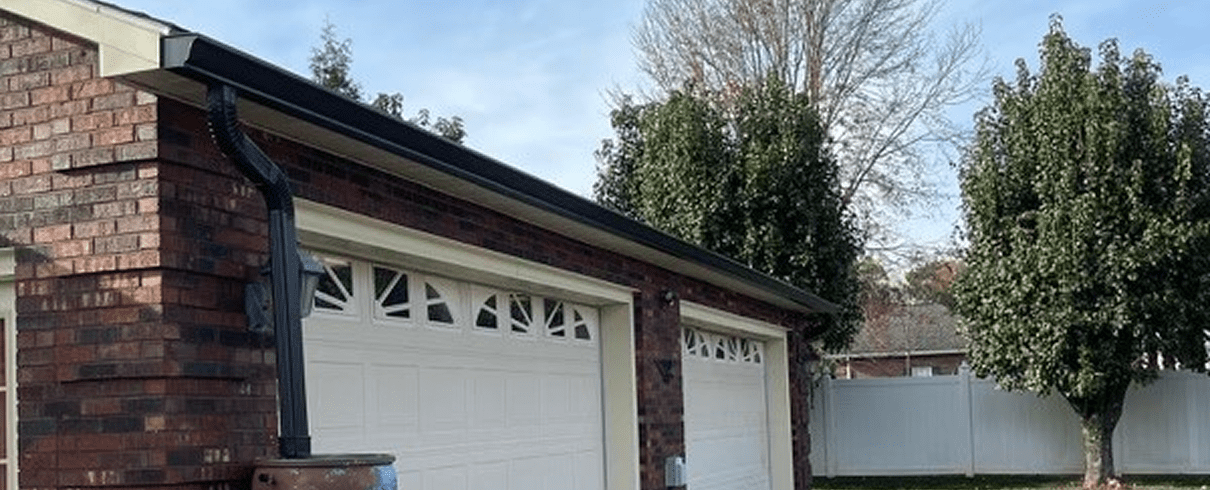 Brick garage with white doors and trees.