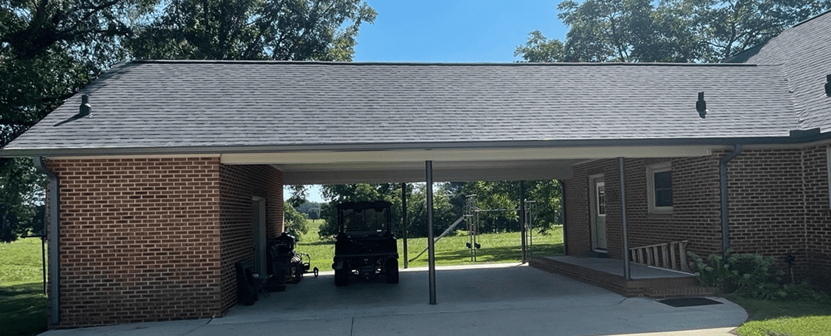 Brick carport with vehicle and greenery.