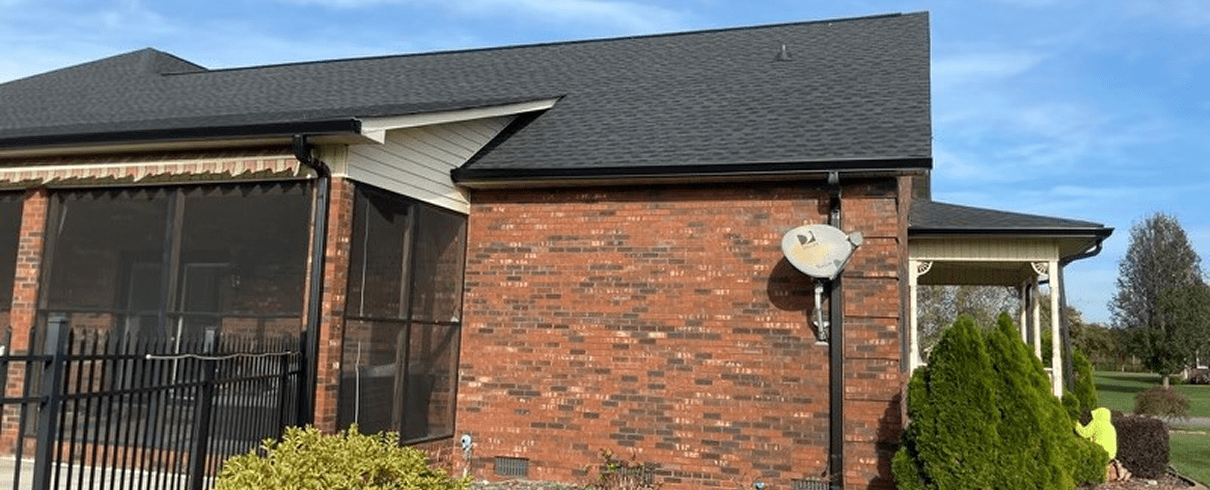 Brick house with black roof and satellite.